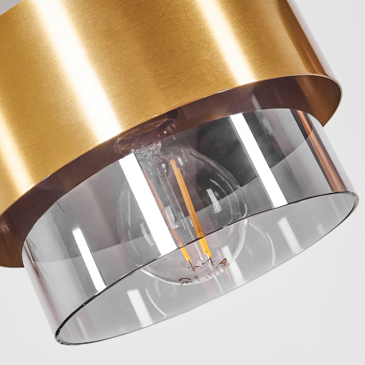 Nahaufnahme einer modernen Lampe. Goldener Metallschirm, Glasdiffusor und sichtbare Glühbirne. Weißer Hintergrund.