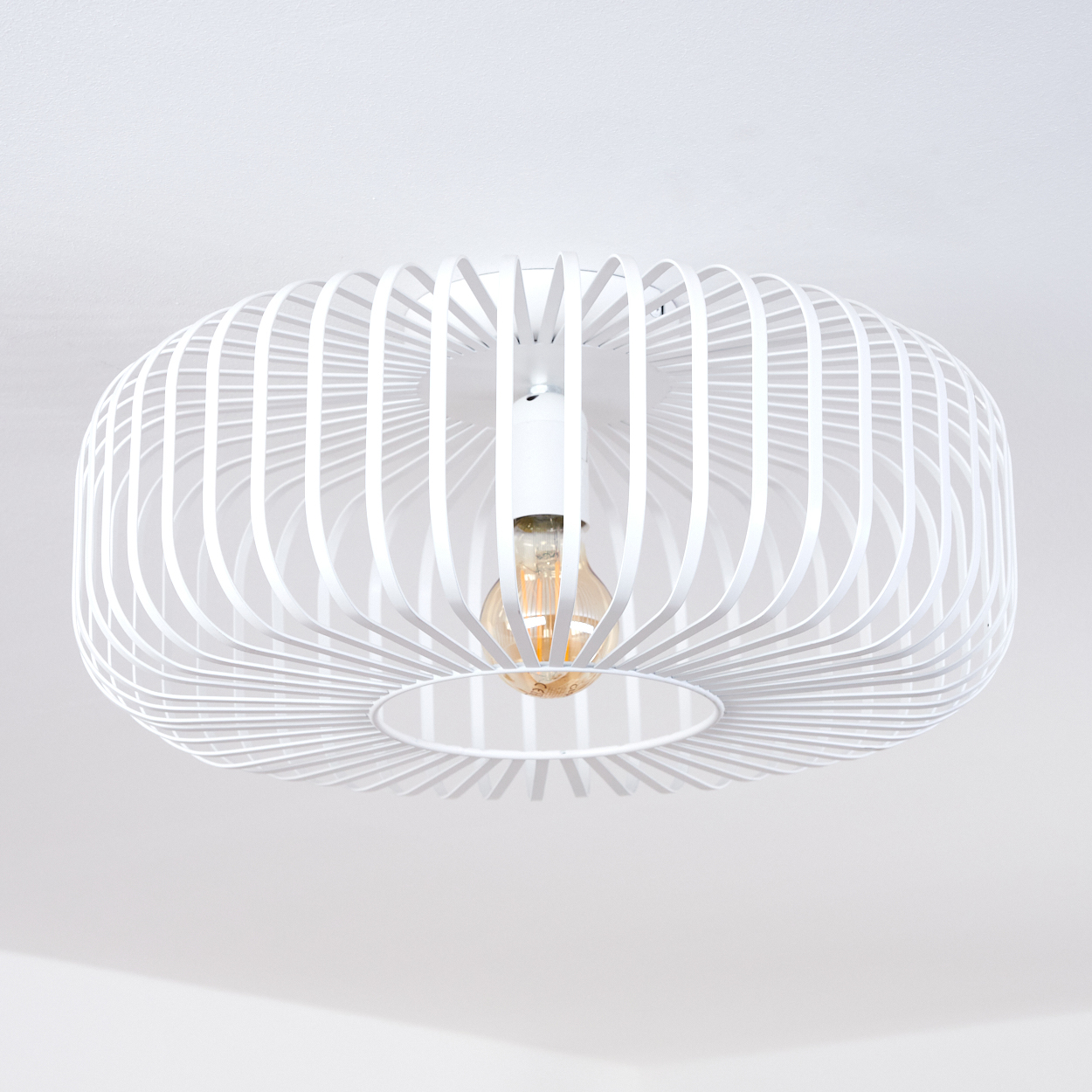 Eine weiße, käfigartige Deckenlampe mit sichtbarer Glühbirne hängt von einer weißen Decke. Die Lampe hat eine runde Form.