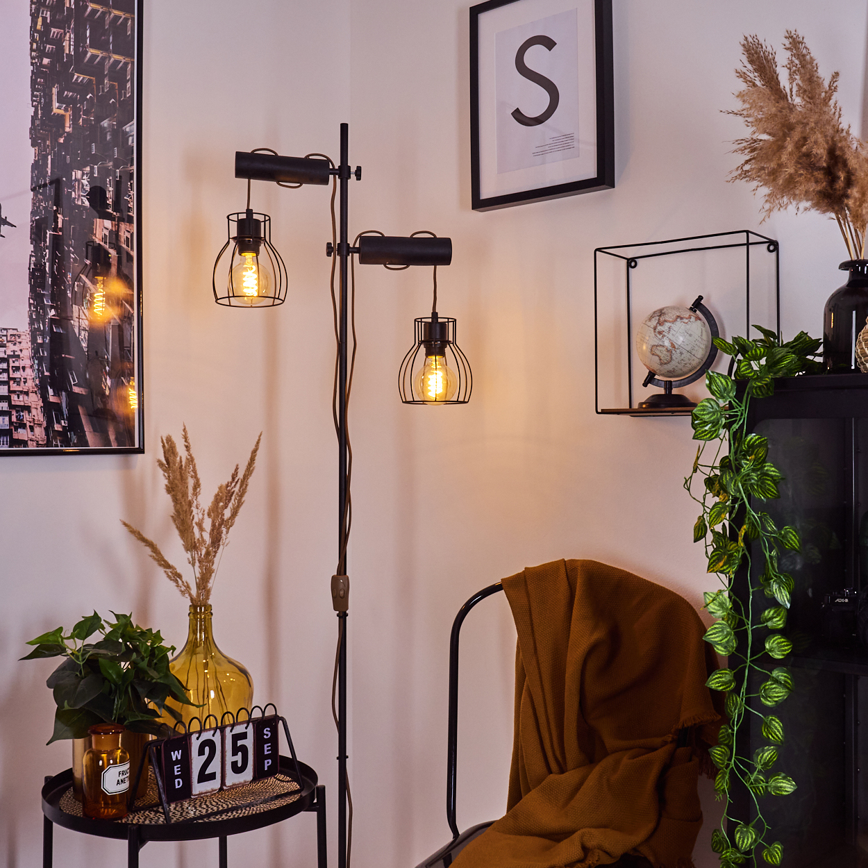 Innenaufnahme: Eine schwarze Lampe, ein Stuhl und ein Tisch mit dekorativen Gegenständen, darunter ein Globus und ein Kalender.