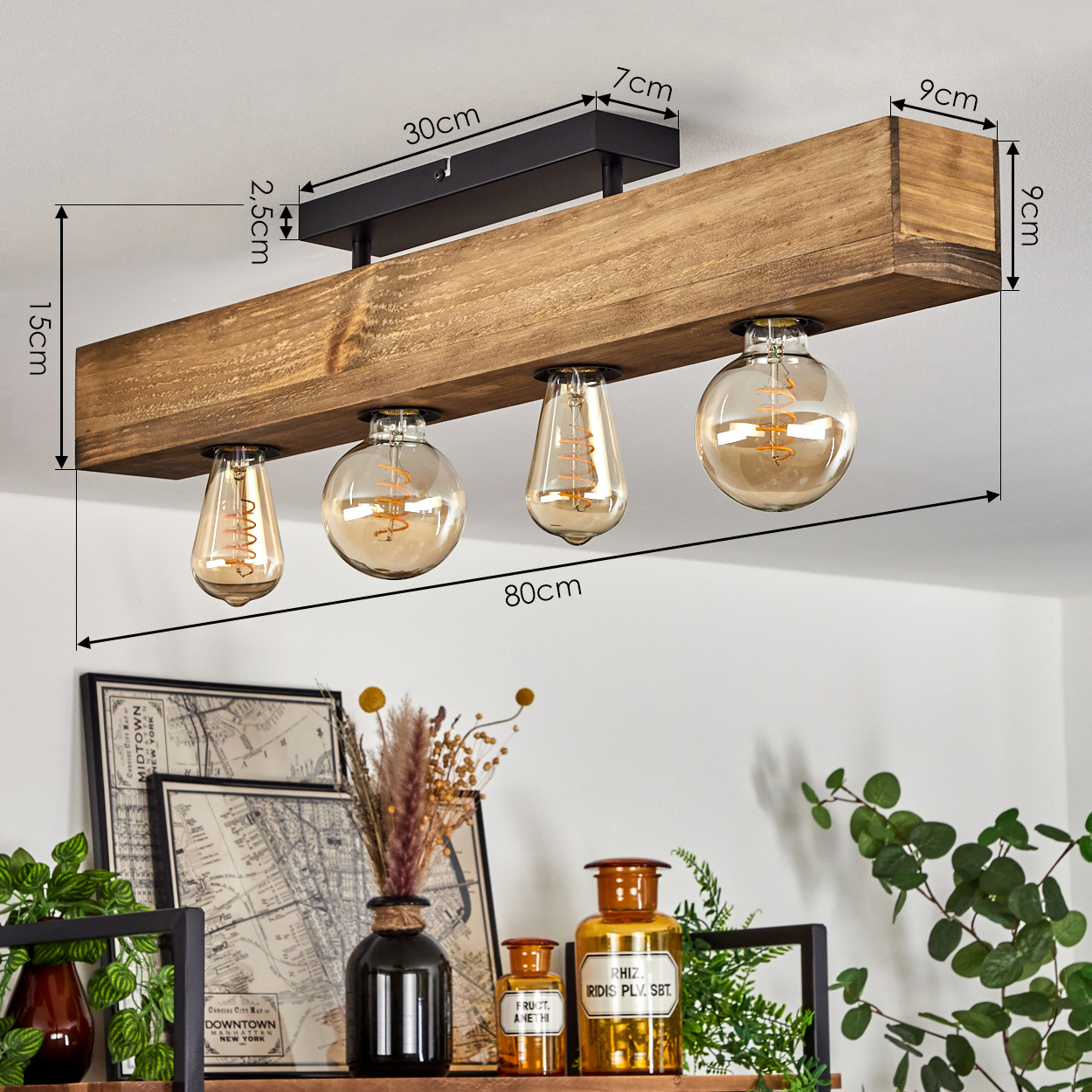 Eine Deckenleuchte aus Holzbalken mit vier Edison-Glühbirnen. Darunter ein Regal mit Karten, Vasen und Pflanzen. Maße sichtbar.