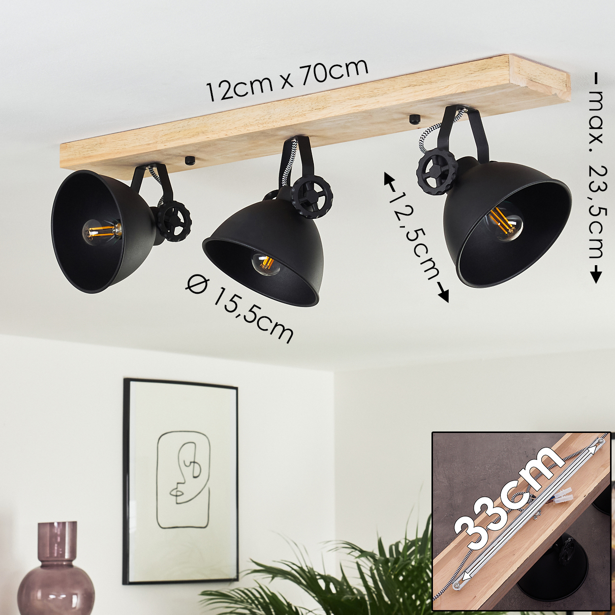 Deckenleuchte mit drei schwarzen Lampen. Holzsockel. Abmessungen sind angegeben. Ein gerahmtes Bild und eine Vase sind sichtbar.