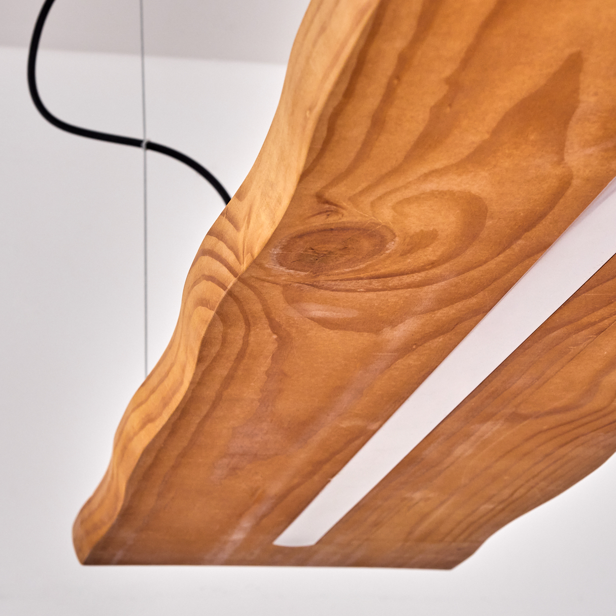 Ein Holzbrett mit weißem Streifen und schwarzem Kabel. Das Holz ist braun und hat eine natürliche Maserung. Weißer Hintergrund.