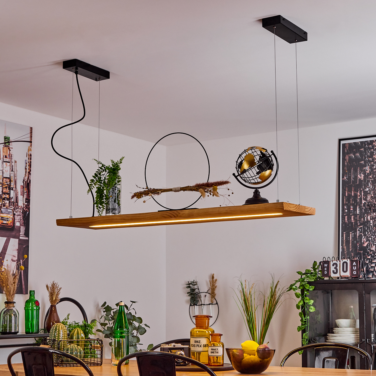 Ein Esszimmer mit Holztisch und Hängelampe. Die Leuchte hat Pflanzen, einen Globus und ein kreisförmiges Design.