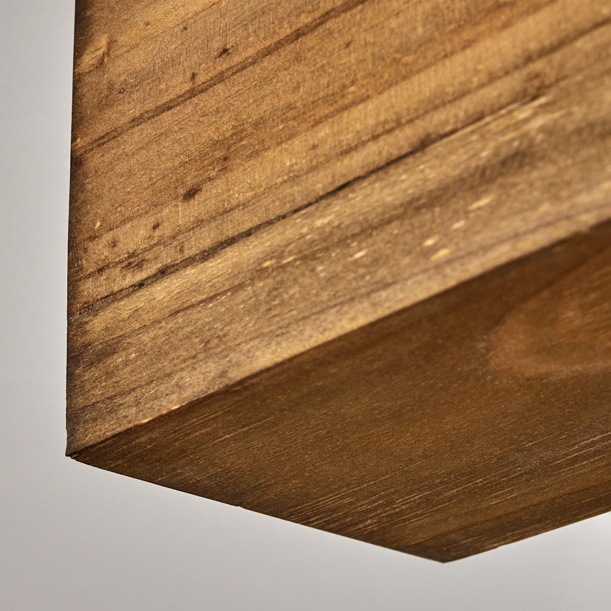 Nahaufnahme einer Holzoberfläche. Das Holz ist braun, mit sichtbarer Maserung und Knoten. Der Hintergrund ist einfarbig weiß.