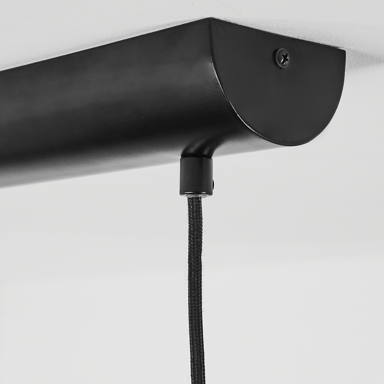 Nahaufnahme einer schwarzen Deckenleuchte. Sie hat eine rechteckige Basis an der Decke, mit einem schwarzen Kabel, das herunterhängt.