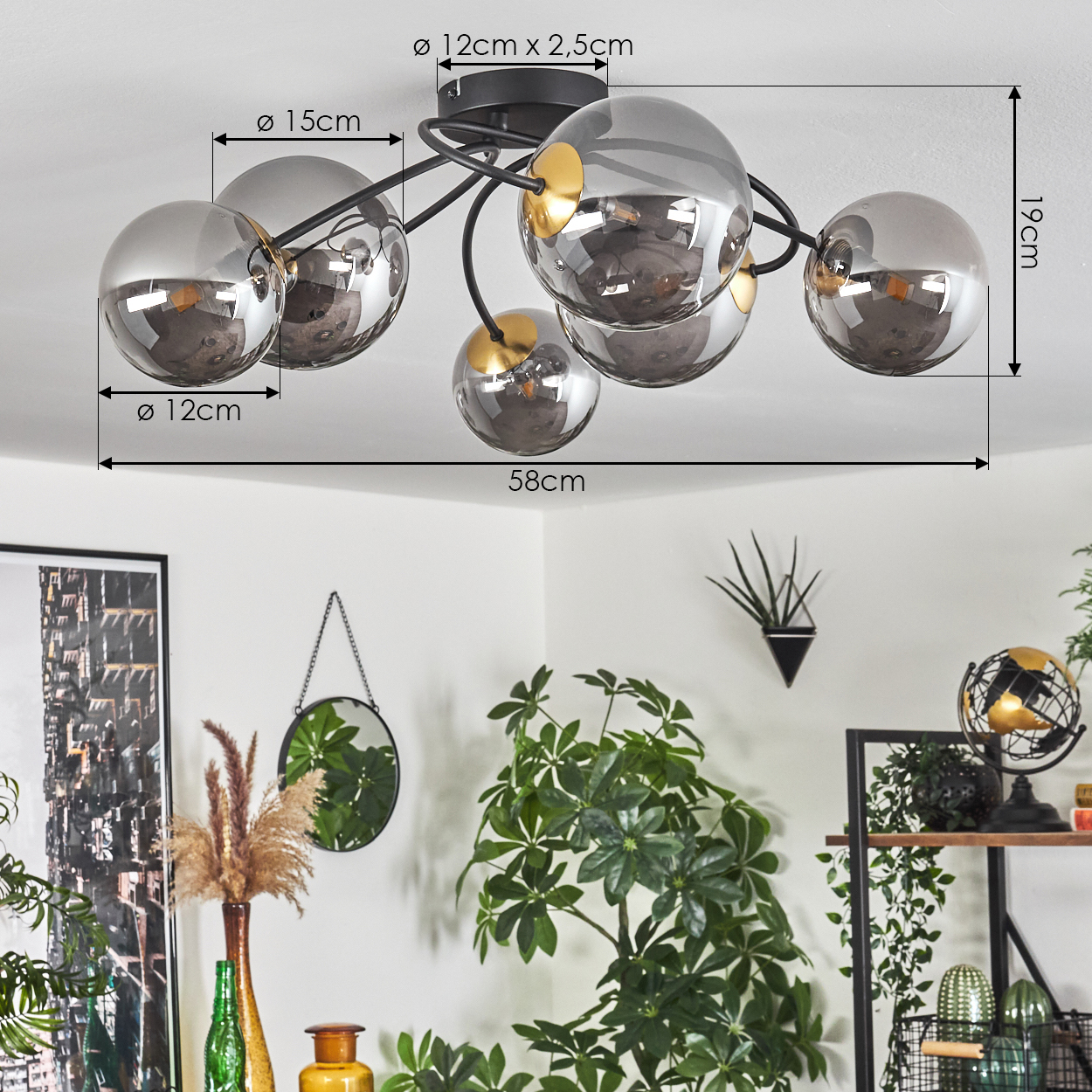 Moderne Deckenlampe mit sechs kugelförmigen Glasschirmen. Abmessungen sind angegeben, sowie eine Raumecke und Pflanzen im Hintergrund.