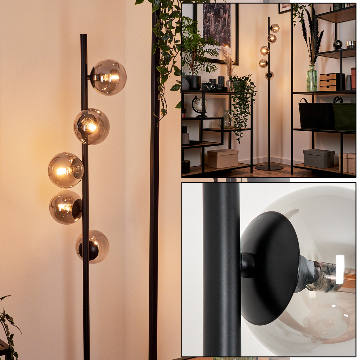 Eine schwarze Stehlampe mit vier Glaskugelleuchten. Der Hintergrund zeigt Regale, Pflanzen und ein gerahmtes Bild.