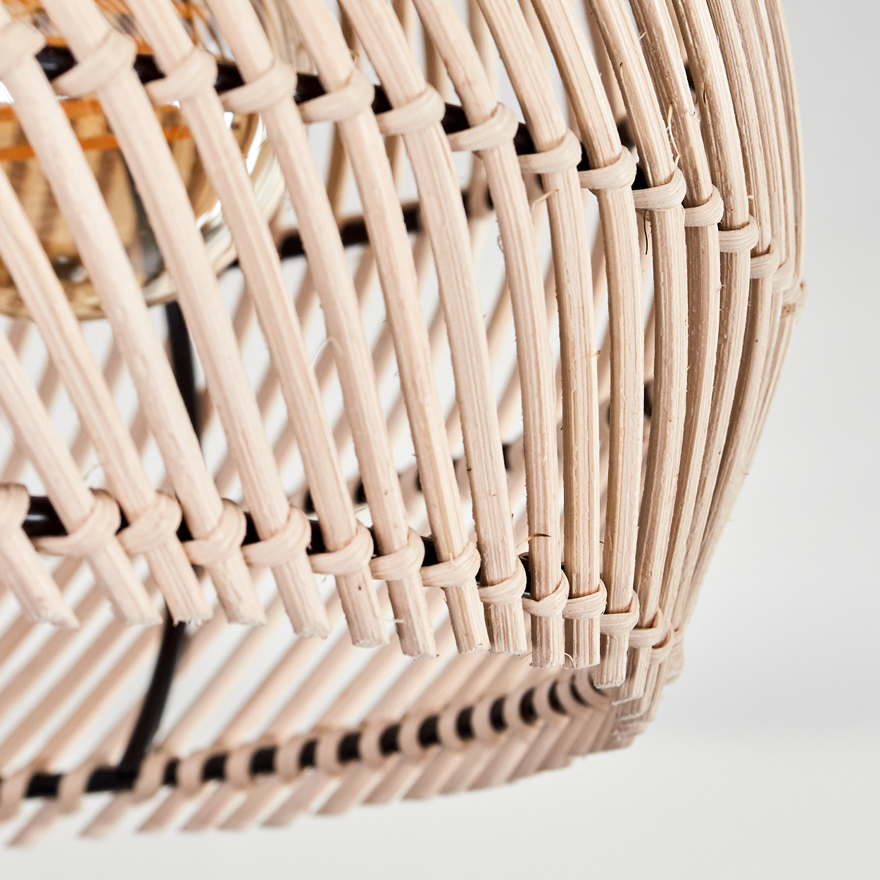 Nahaufnahme eines beigefarbenen Rattan-Lampenschirms. Vertikale und horizontale gewebte Stäbe bilden eine strukturierte Oberfläche.