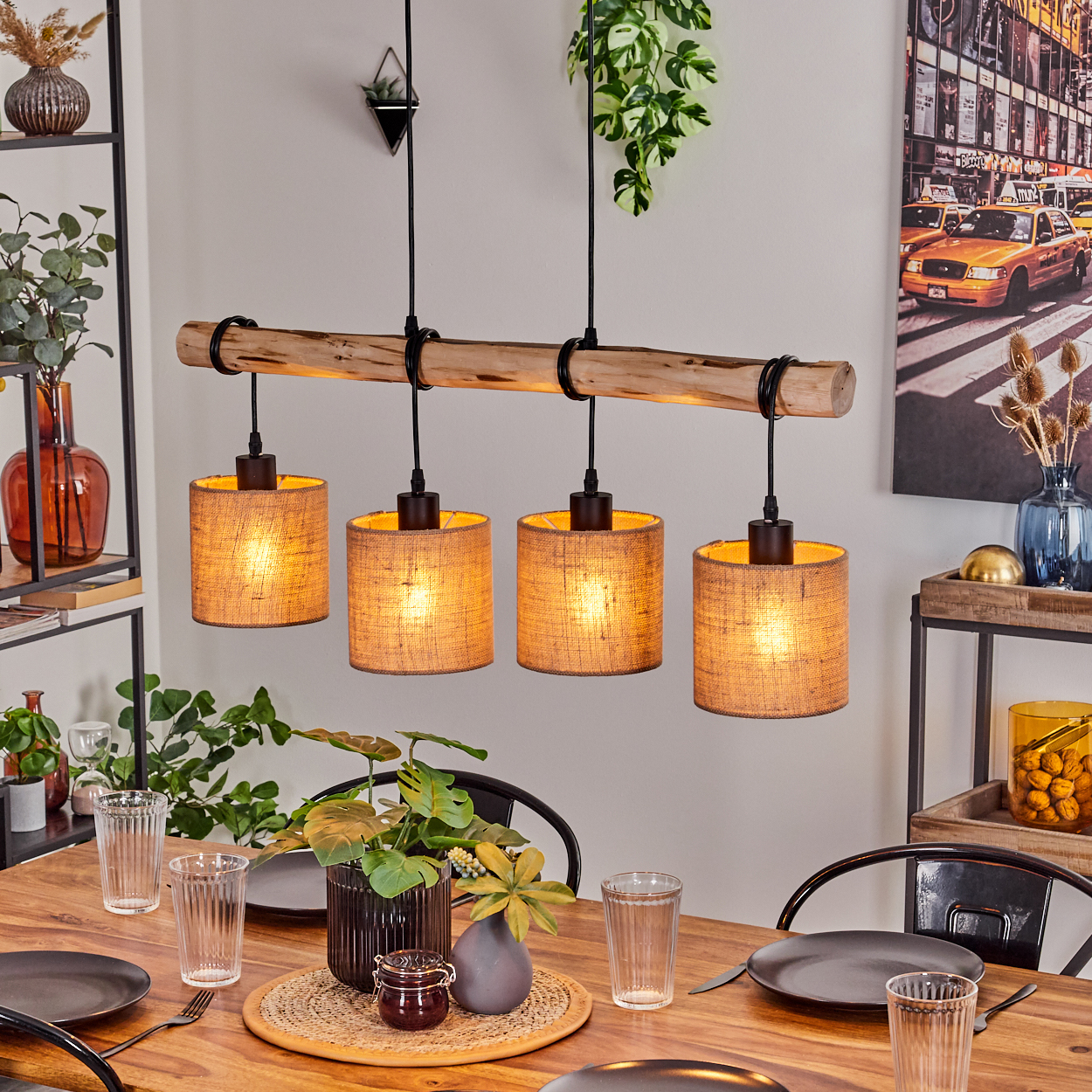 Esszimmer mit Holztisch, vier Hängelampen und Dekoration, darunter Pflanzen und ein gerahmtes Bild.