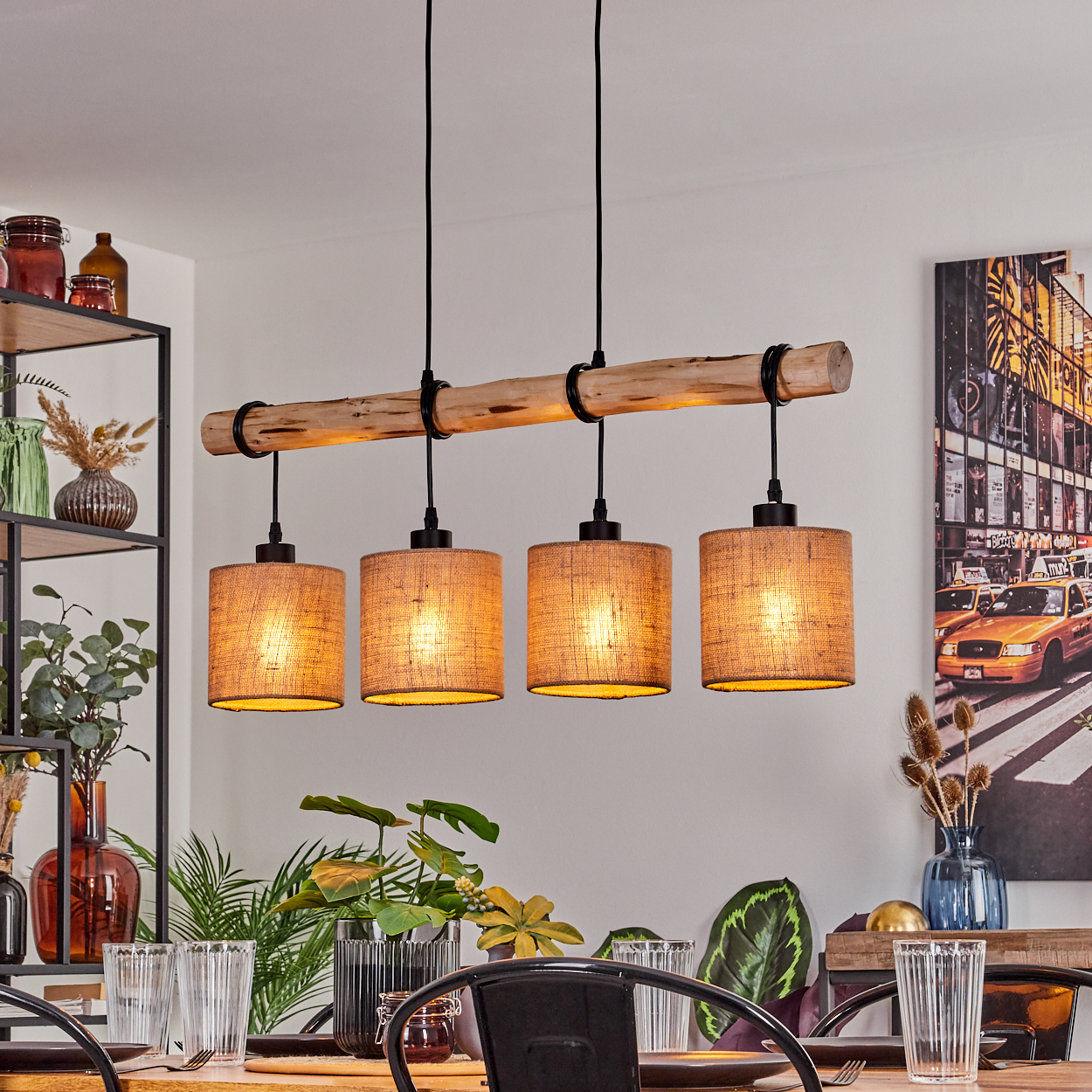 Esszimmer mit Holzbalken-Leuchte. Vier Lampen hängen über einem Tisch. Kunstwerk und Pflanzen im Hintergrund.