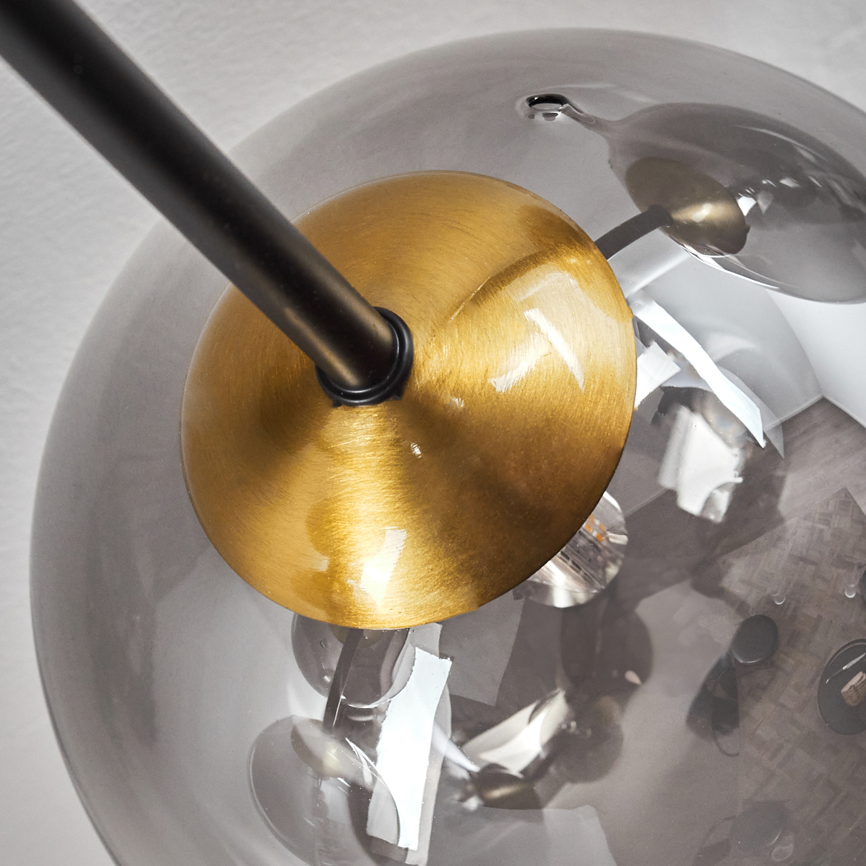 Nahaufnahme einer modernen Lampe. Sie hat eine goldfarbene Kugel, eine graue Glaskugel und eine schwarze Stange.