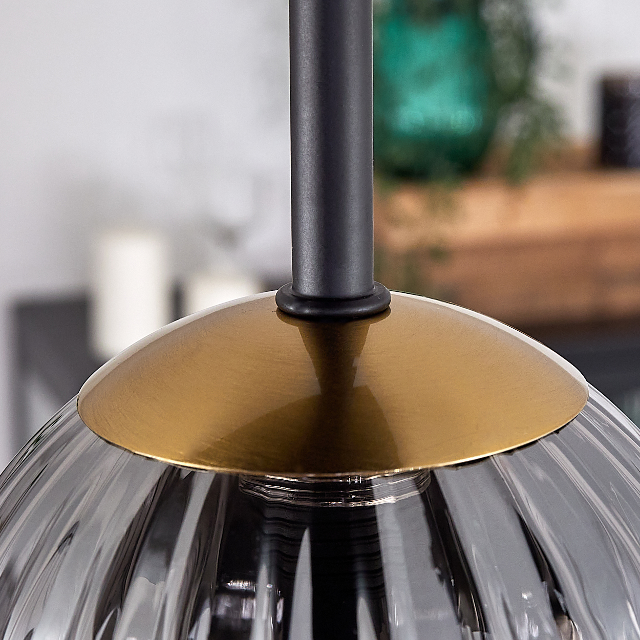Nahaufnahme einer modernen Lampe. Sie hat einen schwarzen Stiel, einen messingfarbenen Schirm und eine geriffelte, graue Glaskugel.