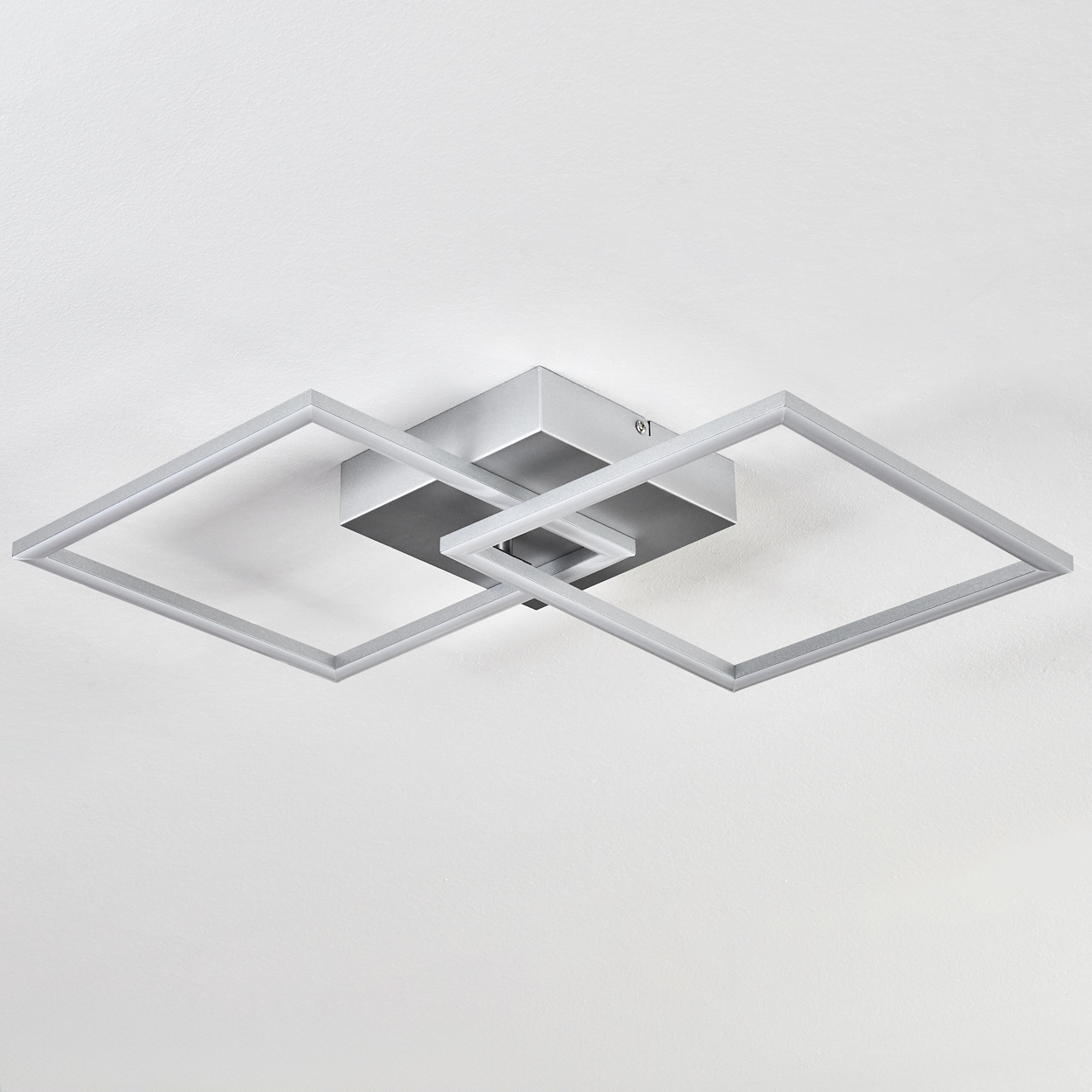 Moderne Deckenleuchte. Sie hat eine quadratische Basis und zwei sich kreuzende quadratische Rahmen. Die Farbe ist Silber, vor weißem Hintergrund.