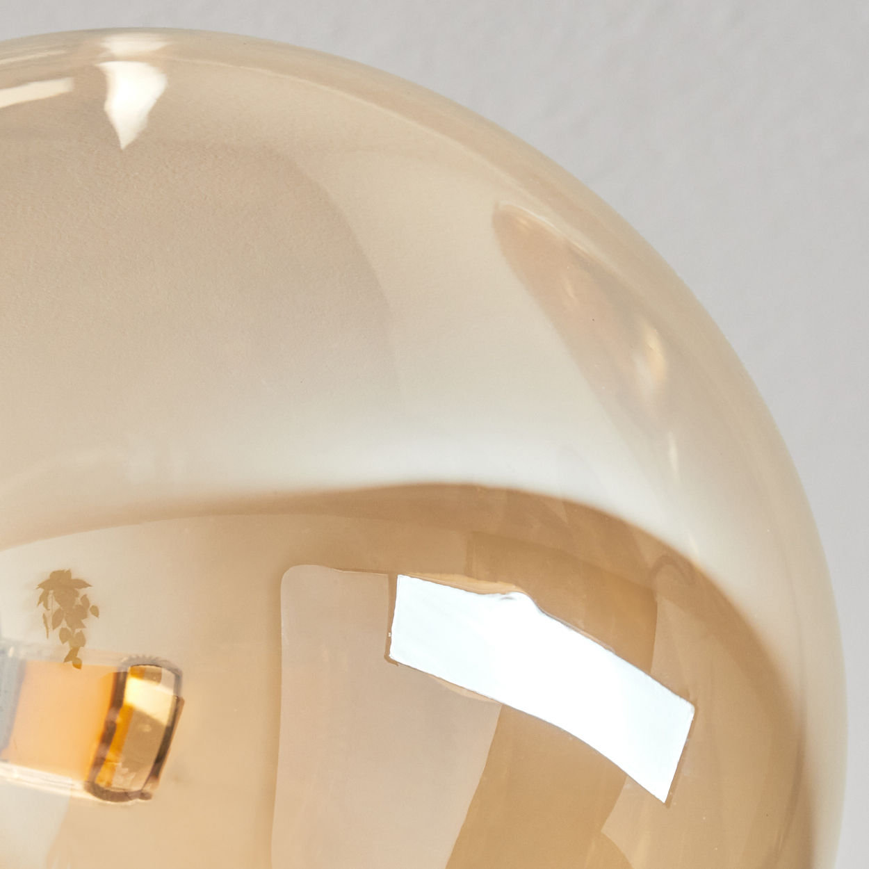Nahaufnahme einer Glühbirne. Die Glühbirne ist beige und transparent, mit hellem Reflex. Der Hintergrund ist schlicht weiß.