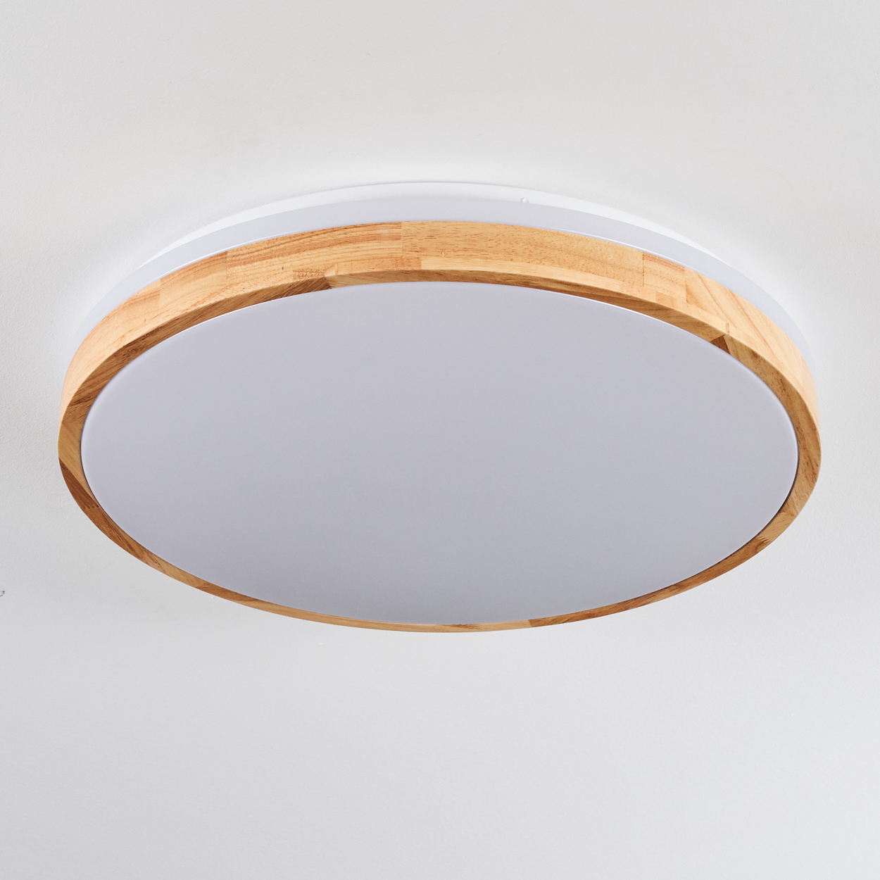 Eine runde Deckenleuchte mit Holzrahmen. Die Lampe hat einen weißen Sockel und eine hellgraue Mitte. Der Hintergrund ist weiß.