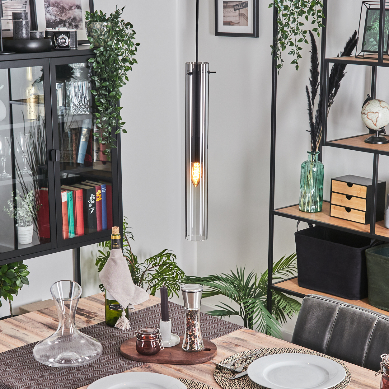 Esszimmer mit Holztisch, gedeckt mit Dekanter, Tellern und Pfeffermühle. Über dem Tisch hängt eine Glaslampe.