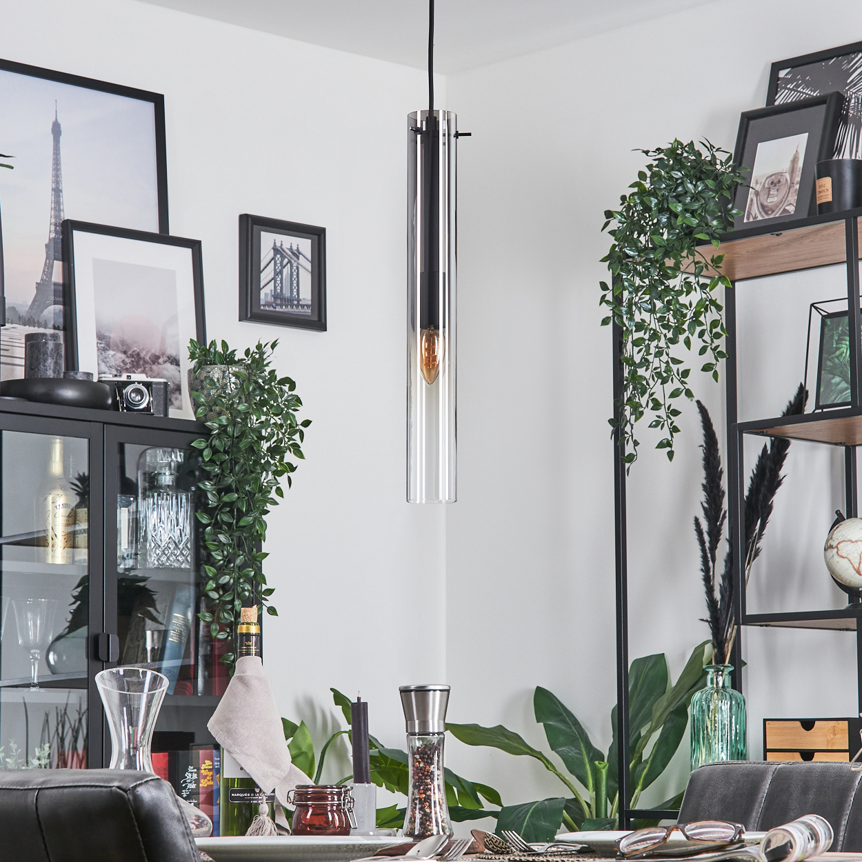 Ein Esszimmer mit Hängelampe, Tischdeko und dekorativen Elementen wie Bildern und Pflanzen.