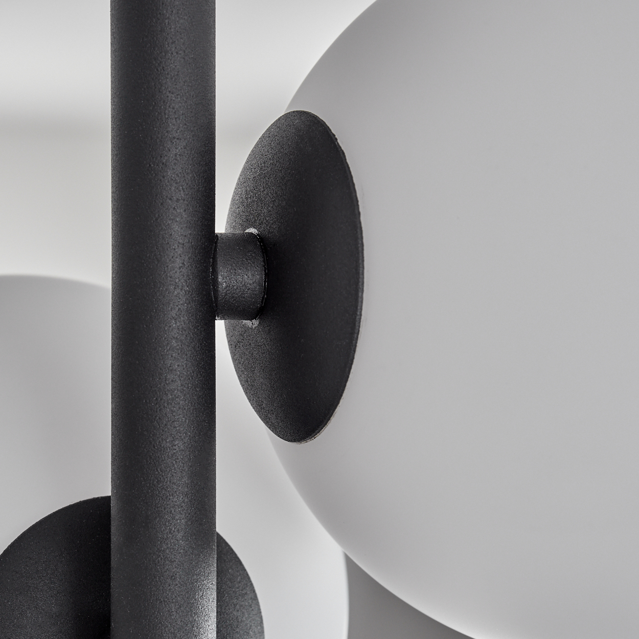 Nahaufnahme einer modernen Lampe. Schwarzer Metallschaft mit weißer Kugel, befestigt durch schwarze Kreiselemente. Weißer Hintergrund.