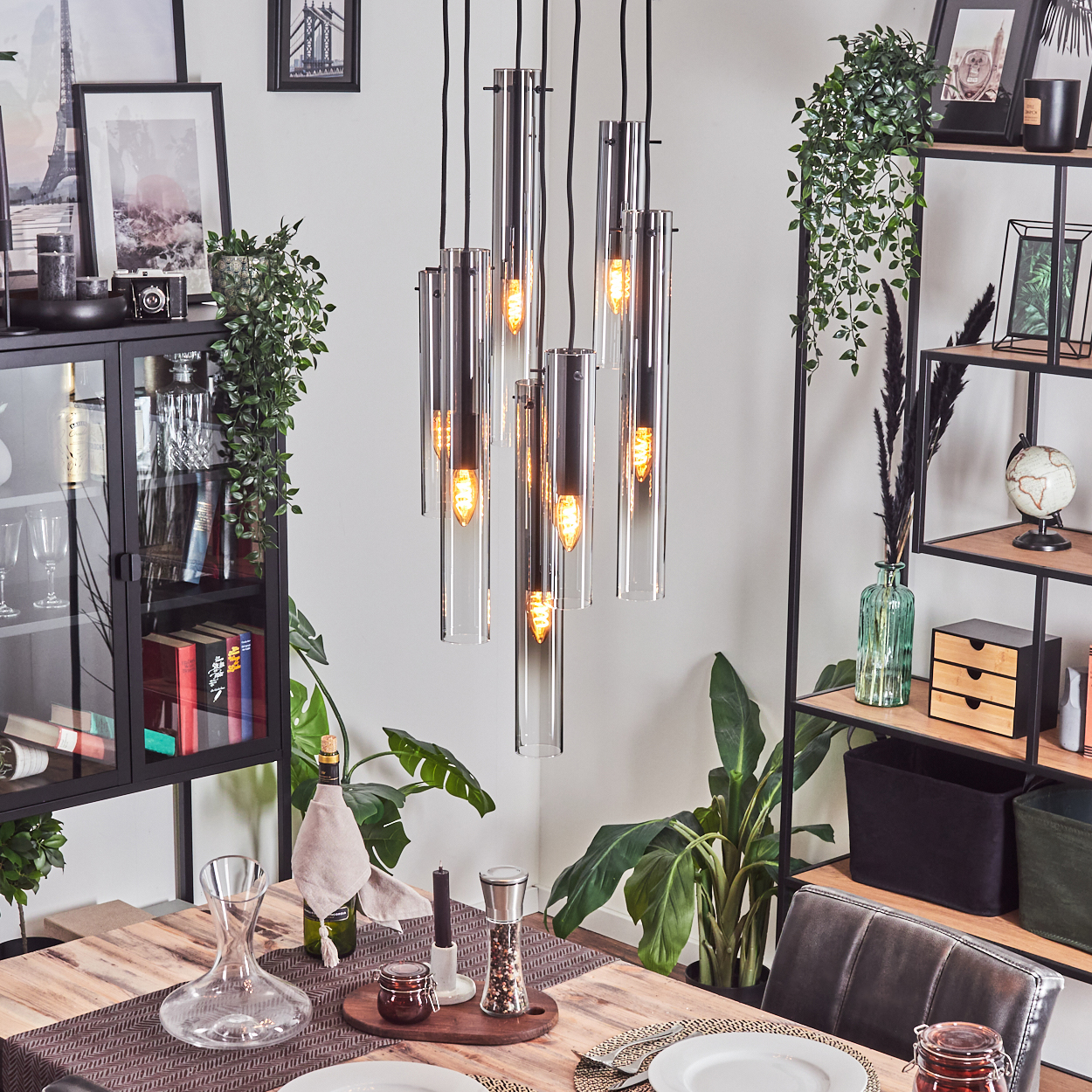 Ein Esszimmer mit einem Holztisch, der mit Tellern und Dekorationen gedeckt ist. Über dem Tisch hängt ein moderner Kronleuchter.