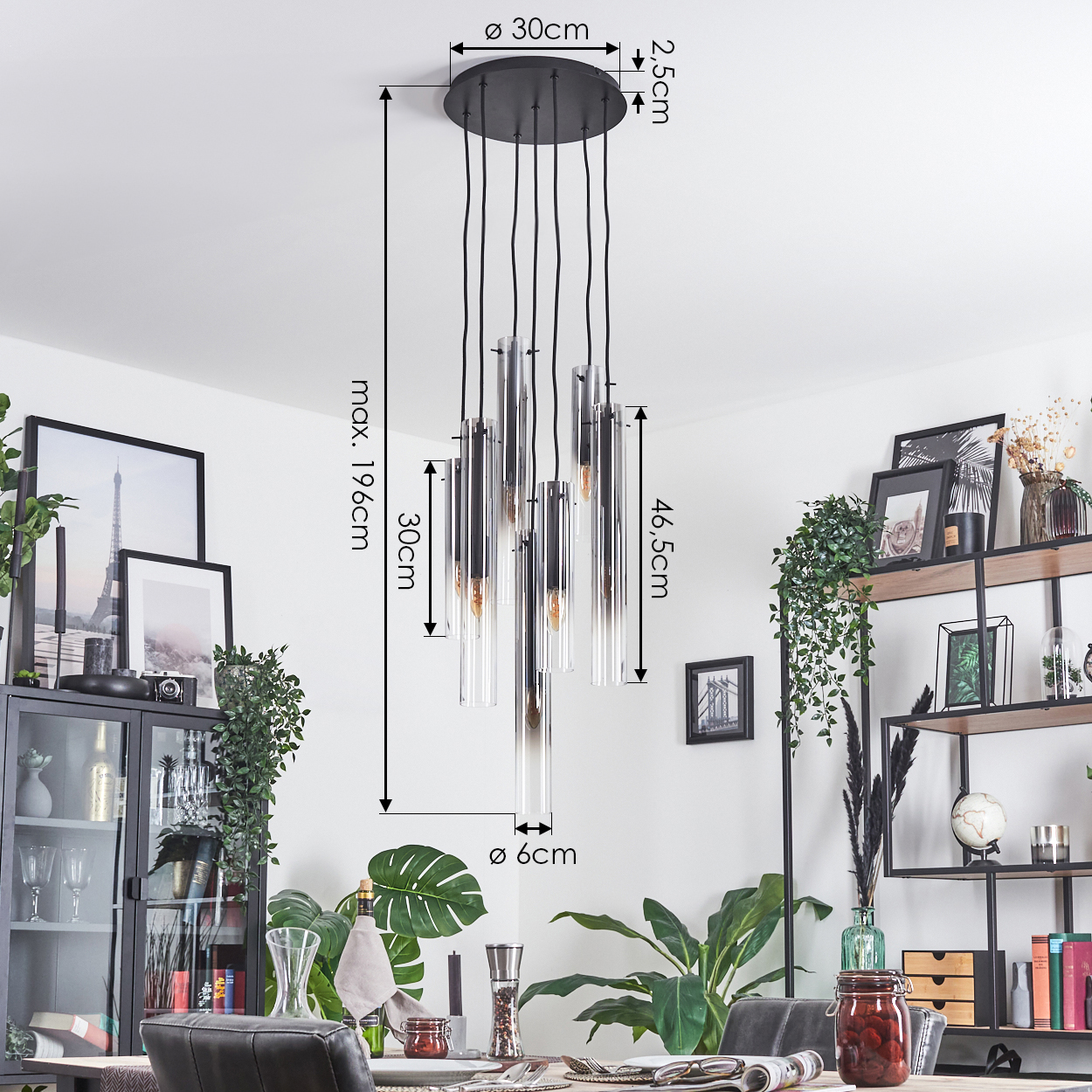 Ein modernes Esszimmer mit einem großen Kronleuchter. Klare Glasröhren hängen über einem Esstisch mit Gedeck.