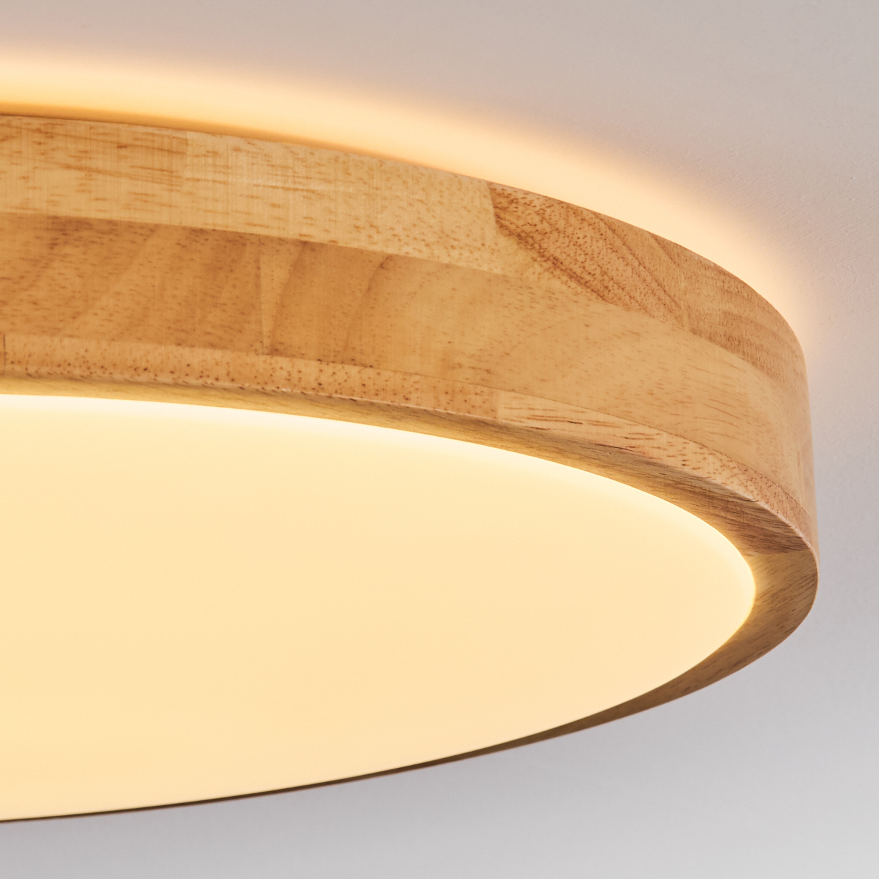 Nahaufnahme einer Deckenleuchte aus Holz. Sie hat einen hellen Holzrahmen und ein helles, weißes Licht. Der Hintergrund ist eine weiße Decke.