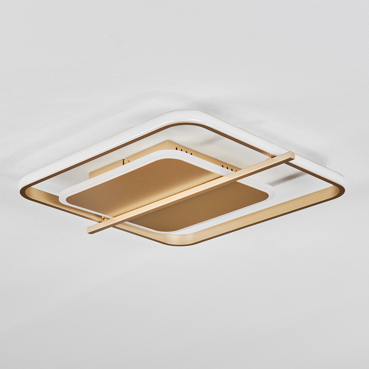 Eine moderne Deckenleuchte mit gold- und weißfarbenen Rechtecken. Sie ist an einer weißen Decke installiert.
