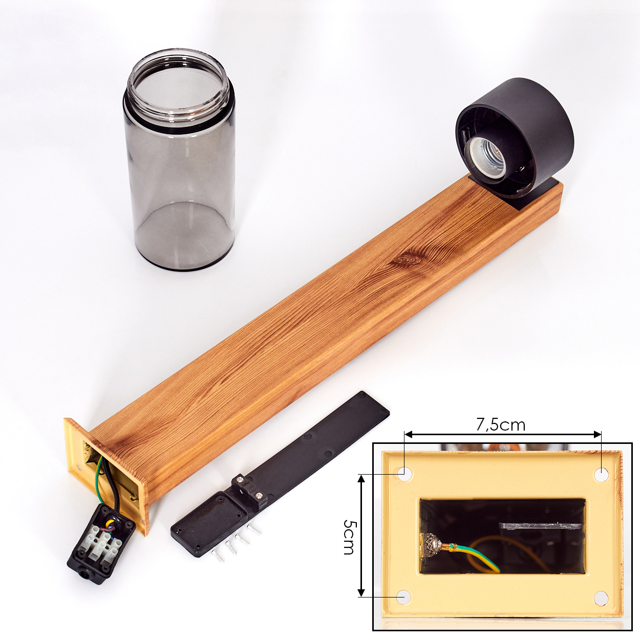 Eine zerlegte Lampe mit Holzteilen, einem Glaszylinder und elektrischen Komponenten liegt vor weißem Hintergrund.
