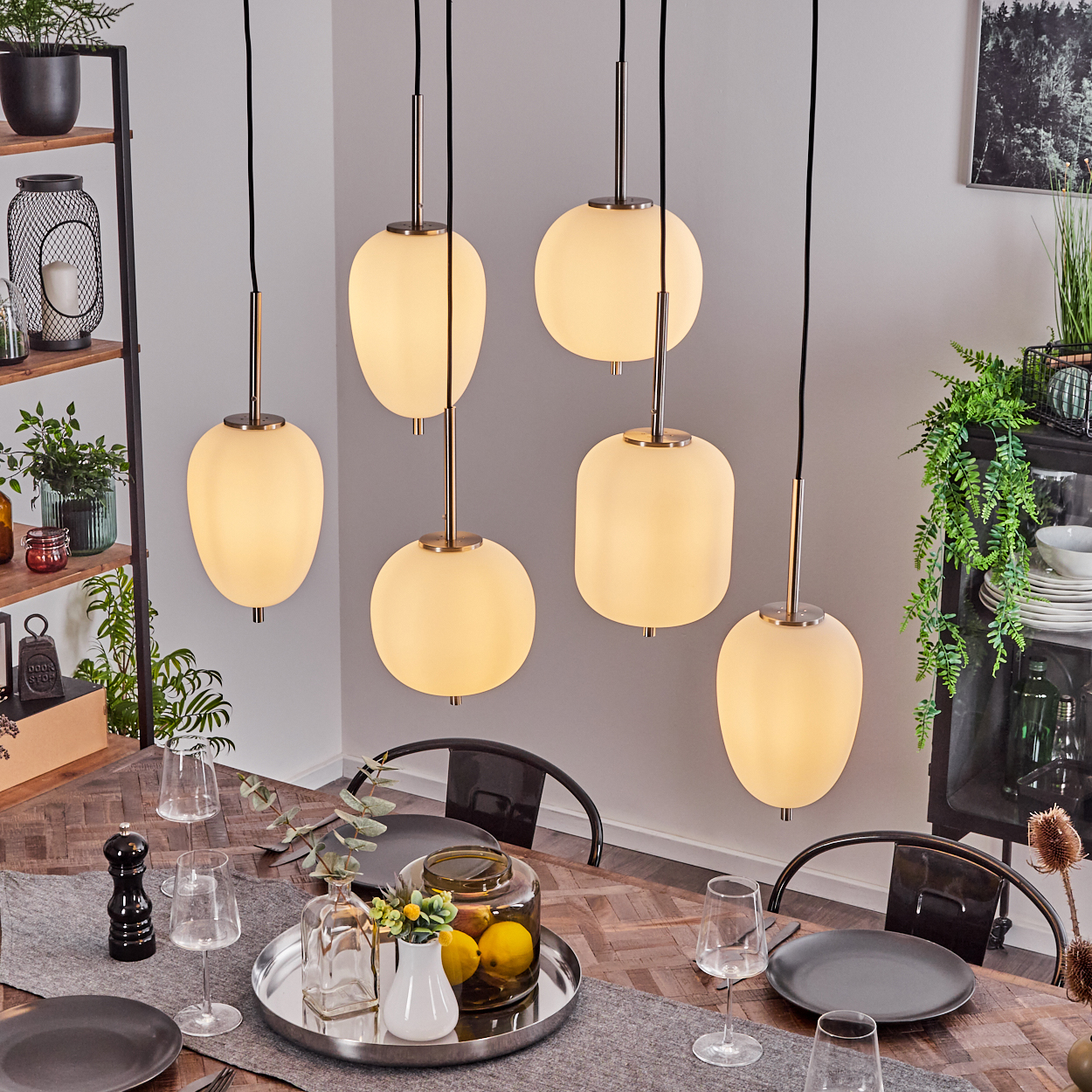 Esszimmer mit Tisch, sechs Pendelleuchten und Dekoration. Der Tisch hat einen Läufer, Teller, Gläser und eine Schale mit Zitronen.