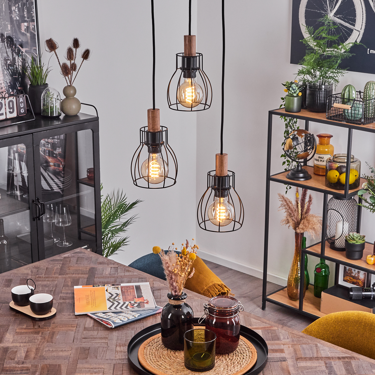 Ein Esszimmer mit Hängelampen, einem Holztisch und verschiedenen dekorativen Gegenständen wie Vasen und einer Zeitschrift.