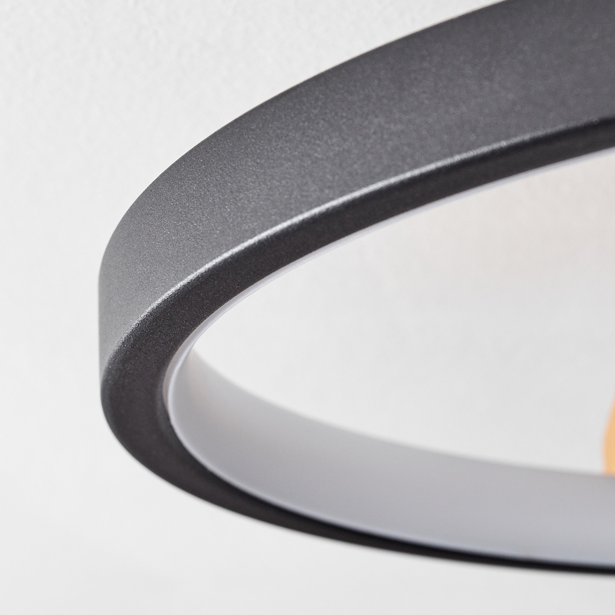 Nahaufnahme einer modernen kreisförmigen Lampe. Die Lampe hat einen dunkelgrauen Außenring mit einem weißen Innenring vor weißem Hintergrund.