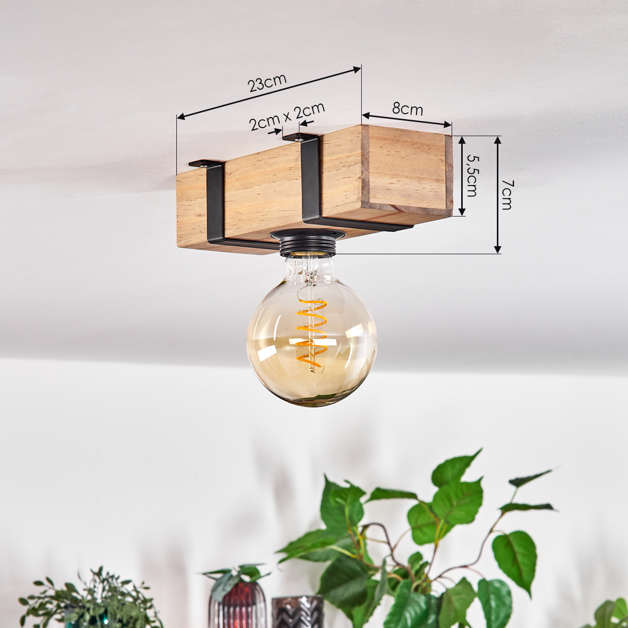 Holzdeckenlampe mit großer Glühbirne. Abmessungen sind angegeben. Grüne Pflanzen und dekorative Vasen im Hintergrund.