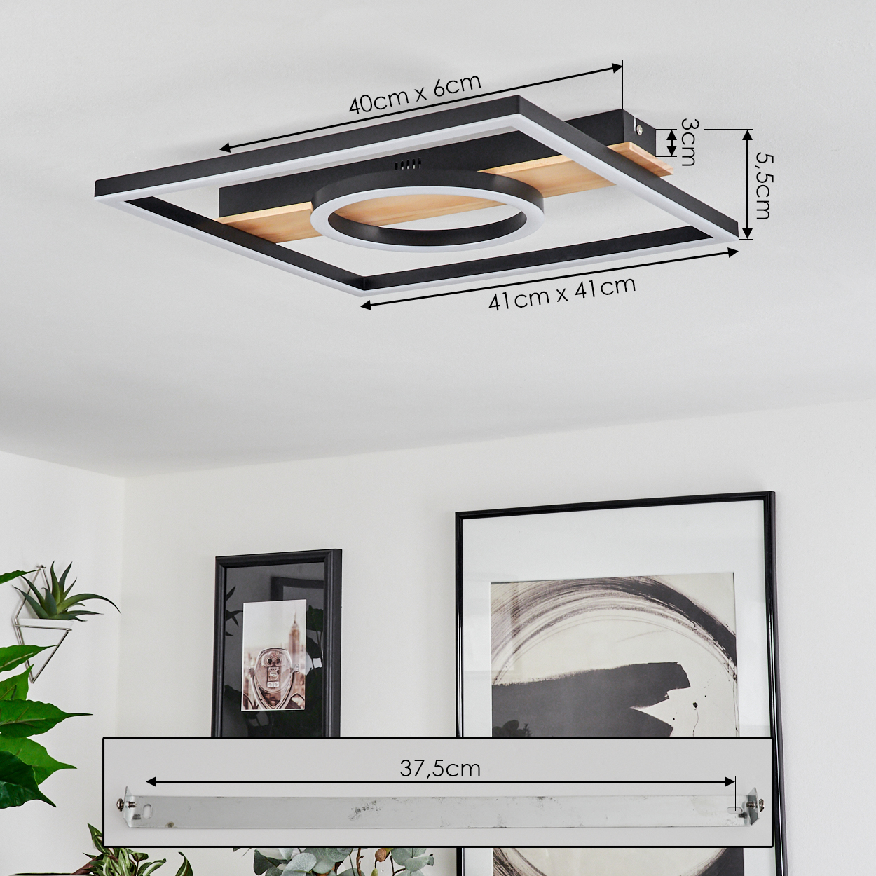 Eine Deckenlampe mit quadratischem Rahmen und kreisförmigem Licht. Abmessungen sind angegeben. Kunst und Pflanze sind im Hintergrund sichtbar.