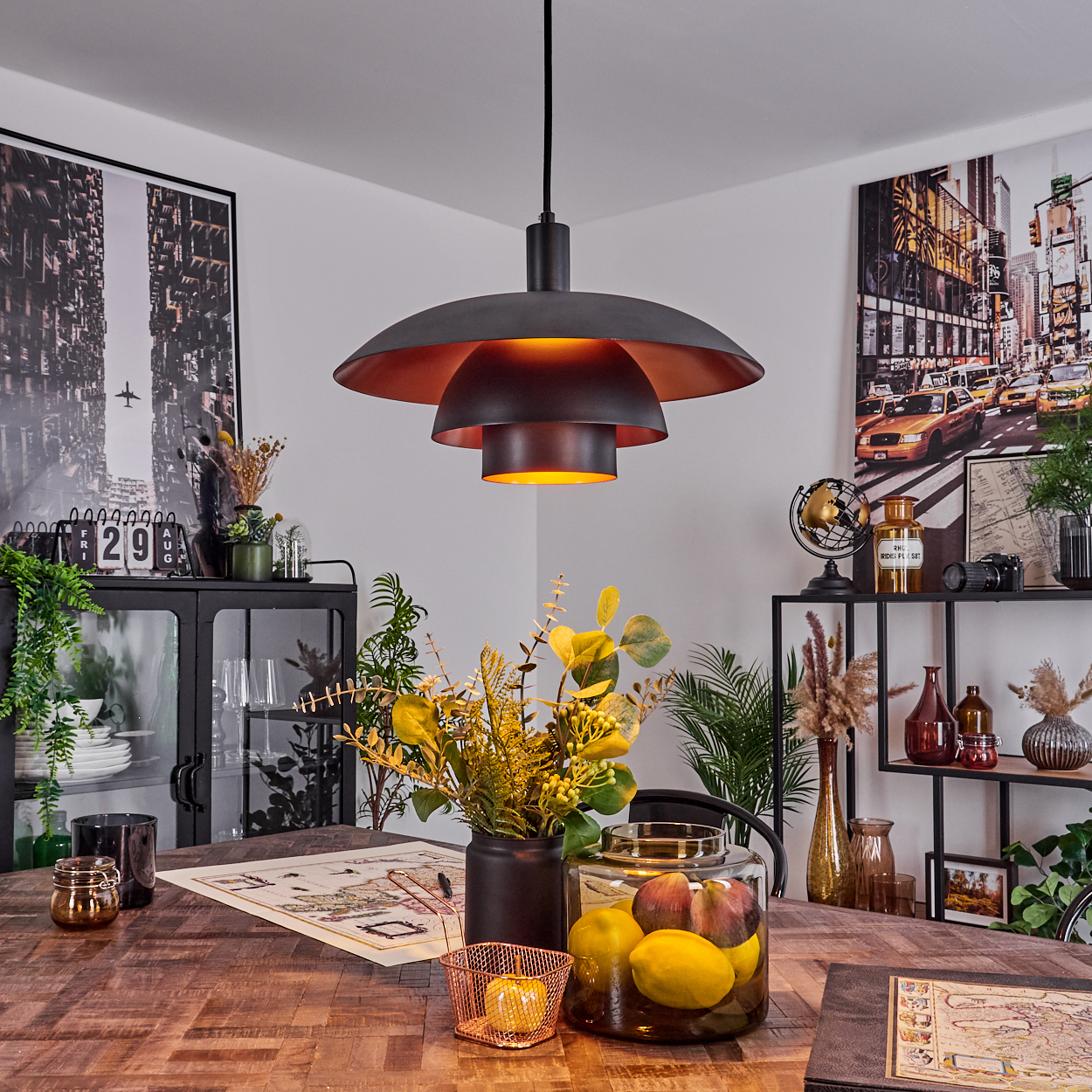 Ein Esszimmer mit Holztisch, schwarzer Lampe und Dekorationen wie Blumen und gerahmten Bildern.