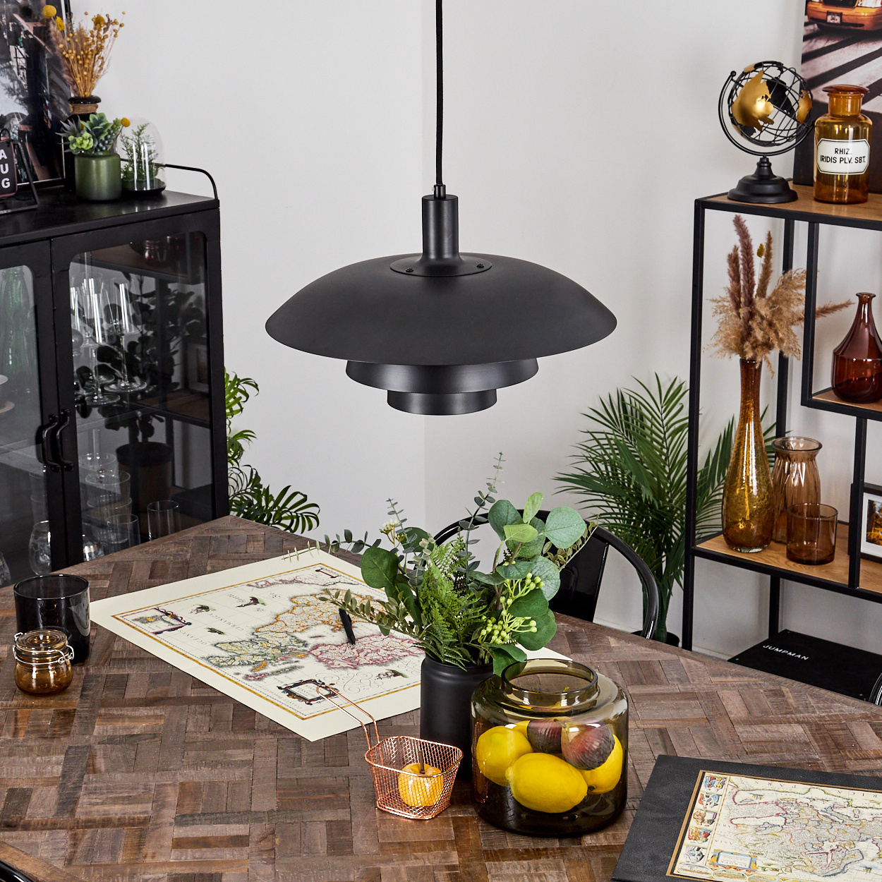 Ein Esszimmer mit Holztisch, schwarzer Lampe und dekorativen Elementen wie Vasen und einer Karte.