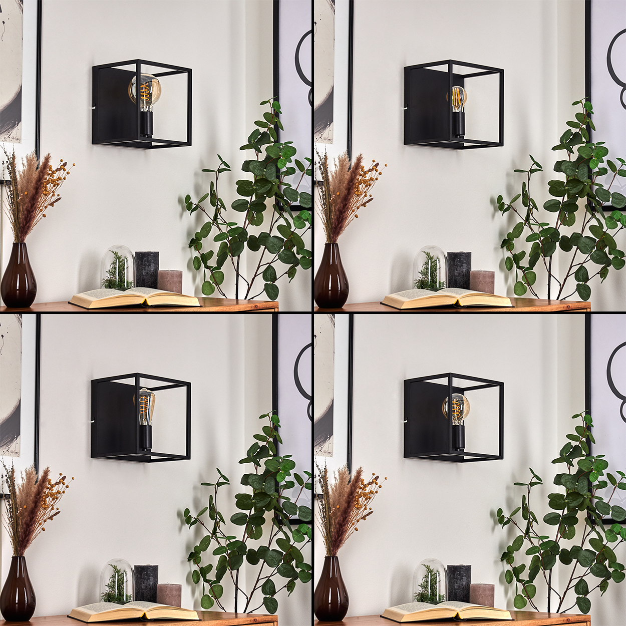 Eine schwarze, würfelförmige Wandlampe mit einer Glühbirne. Darunter ein Holzregal mit Vasen, Büchern, Kerzen und Pflanzen vor einer weißen Wand.