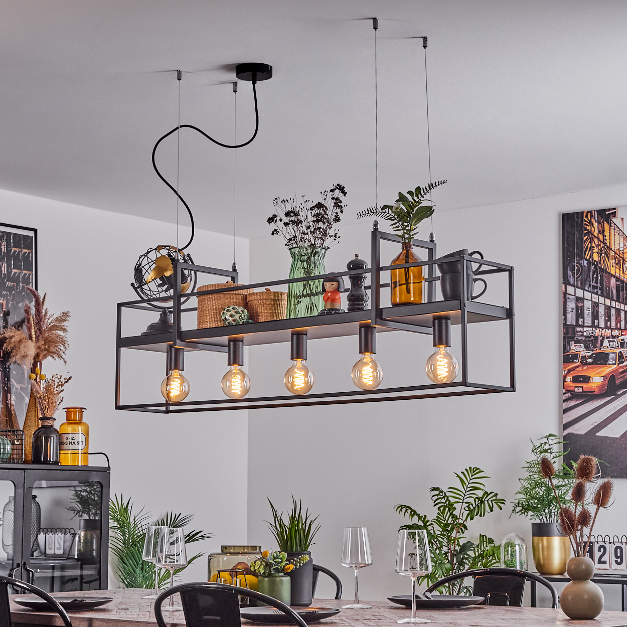 Eine moderne Hängelampe mit fünf Glühbirnen, Regalen mit Dekoration und einem Esstisch, mit Pflanzen und einem NYC-Bild.