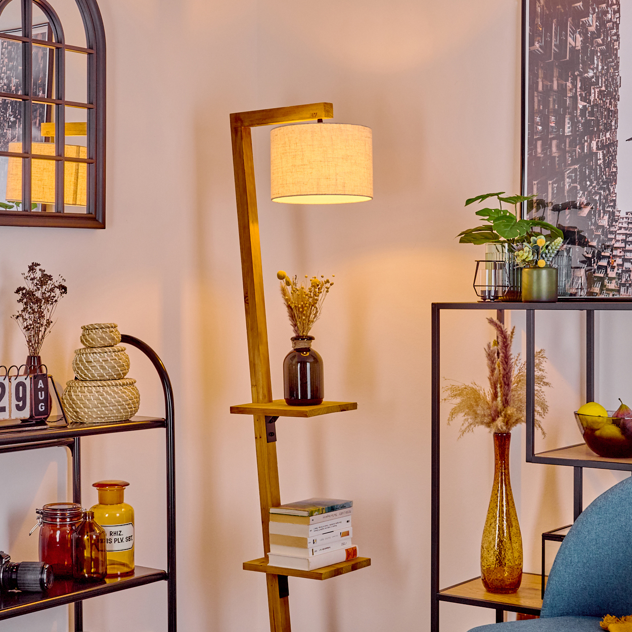 Ein Raum mit einer hölzernen Stehlampe, Regalen und Dekoration. Enthält einen Spiegel, Vasen mit Blumen, Bücher und einen blauen Stuhl.
