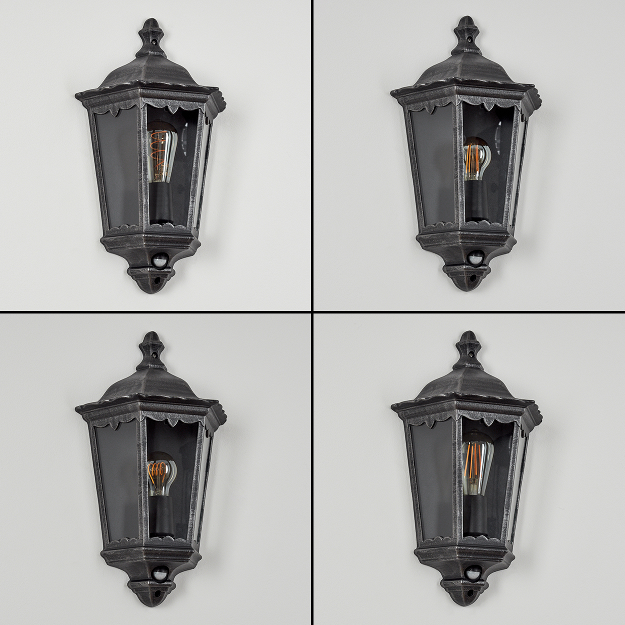 Vier antike Wandlampen mit Glasplatten und Edison-Glühbirnen vor einer weißen Wand. Die Lampen sind dunkelgrau.