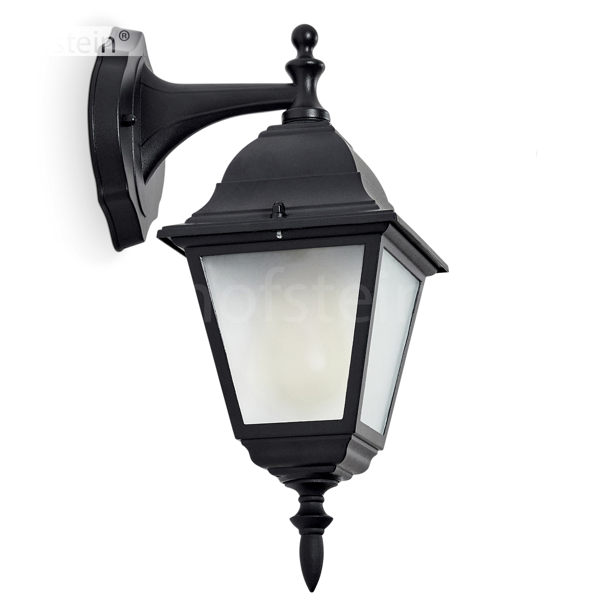 Eine schwarze Außenwandleuchte mit dekorativem Design, an einer weißen Wand befestigt. Sie hat eine Glasscheibe und eine spitz zulaufende Unterseite.