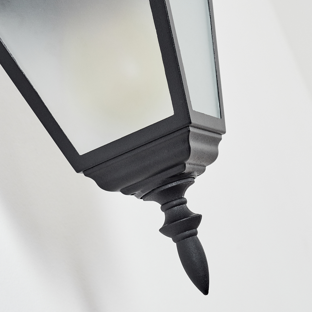 Gezeigt wird eine schwarze, verzierte Außenlampe. Die Lampe ist abgewinkelt und zeigt ihre Form und Details vor weißem Hintergrund.
