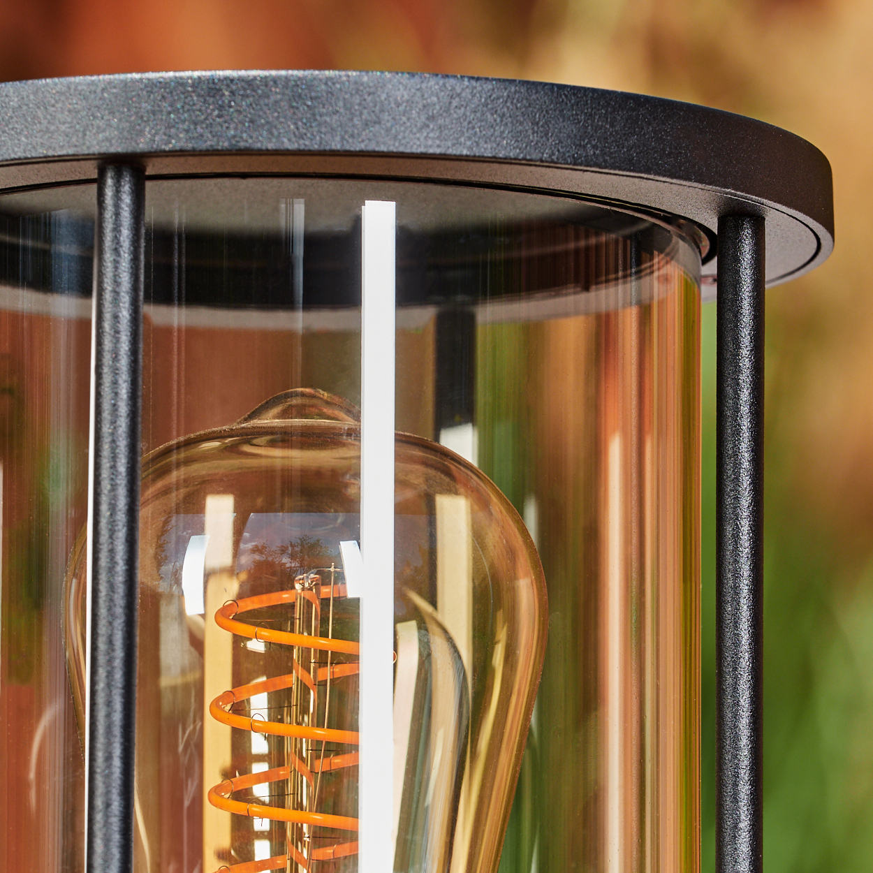 Nahaufnahme einer dekorativen Lampe. Sie hat eine Glühbirne im Vintage-Stil mit orangefarbenem Glühfaden in einem Glasgehäuse.