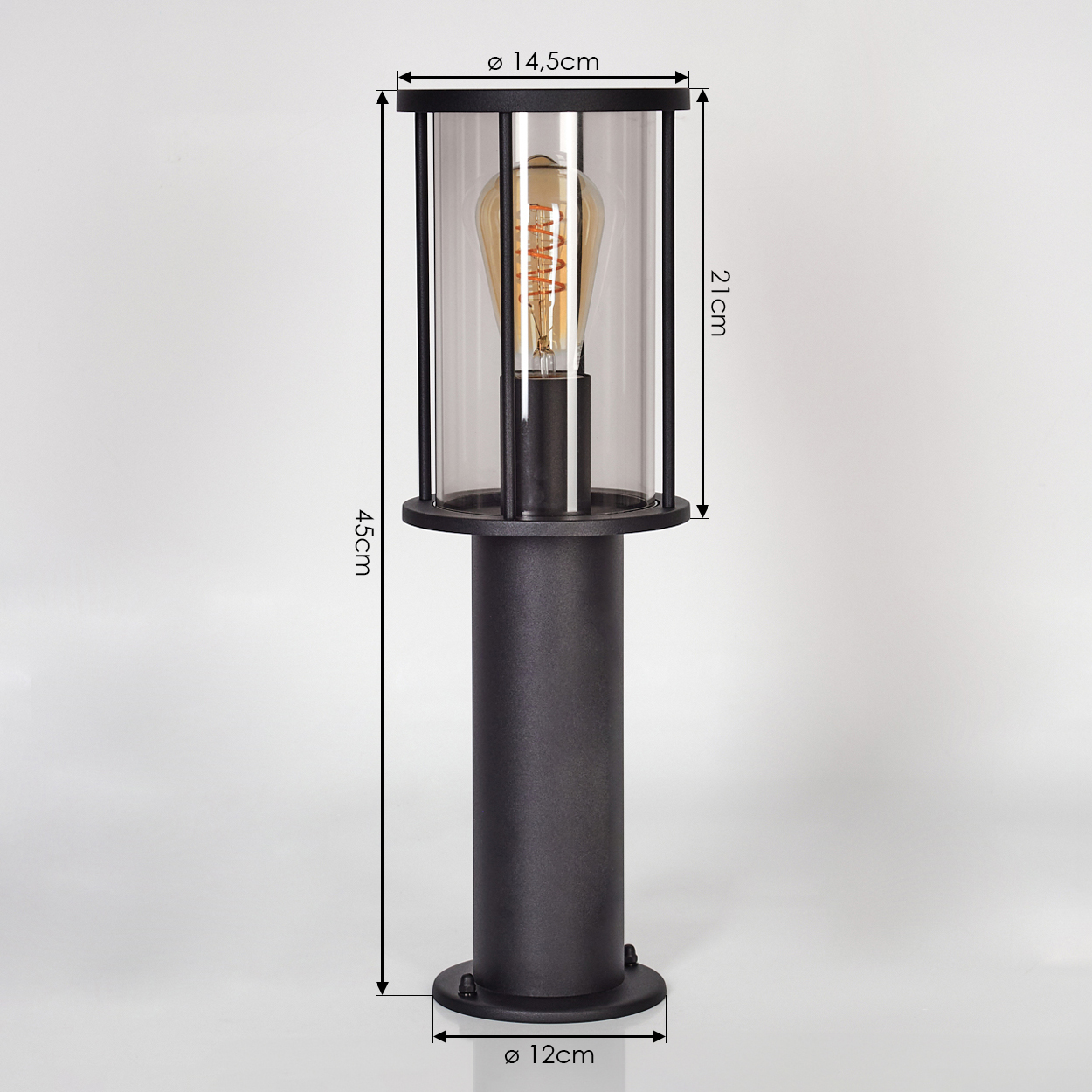 Eine schwarze Außenlampe mit zylindrischer Glasabdeckung. Sie hat eine sichtbare Glühbirne. Abmessungen sind angegeben.
