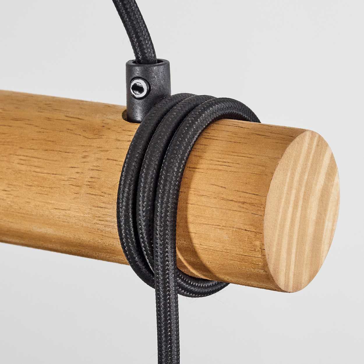 Holzzylinder mit schwarzem Kabel, das darum gewickelt ist. Ein Verbinder hält das Kabel. Der Hintergrund ist ein weißer Farbverlauf.