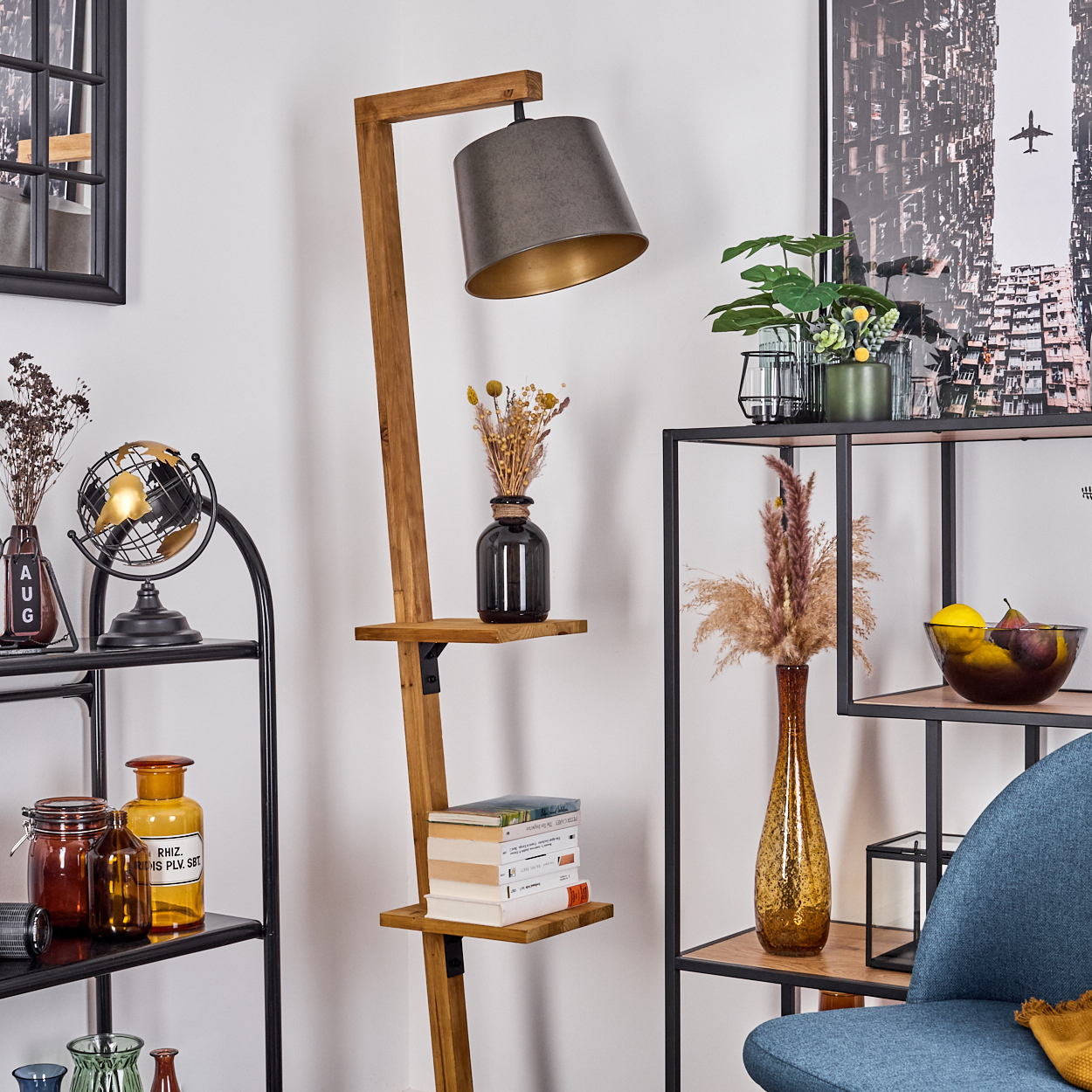 Ein Raum mit einer Holzlampe, Regalen mit Dekoration, einem Globus, Büchern und einem blauen Stuhl. Ein Bild hängt an der Wand.