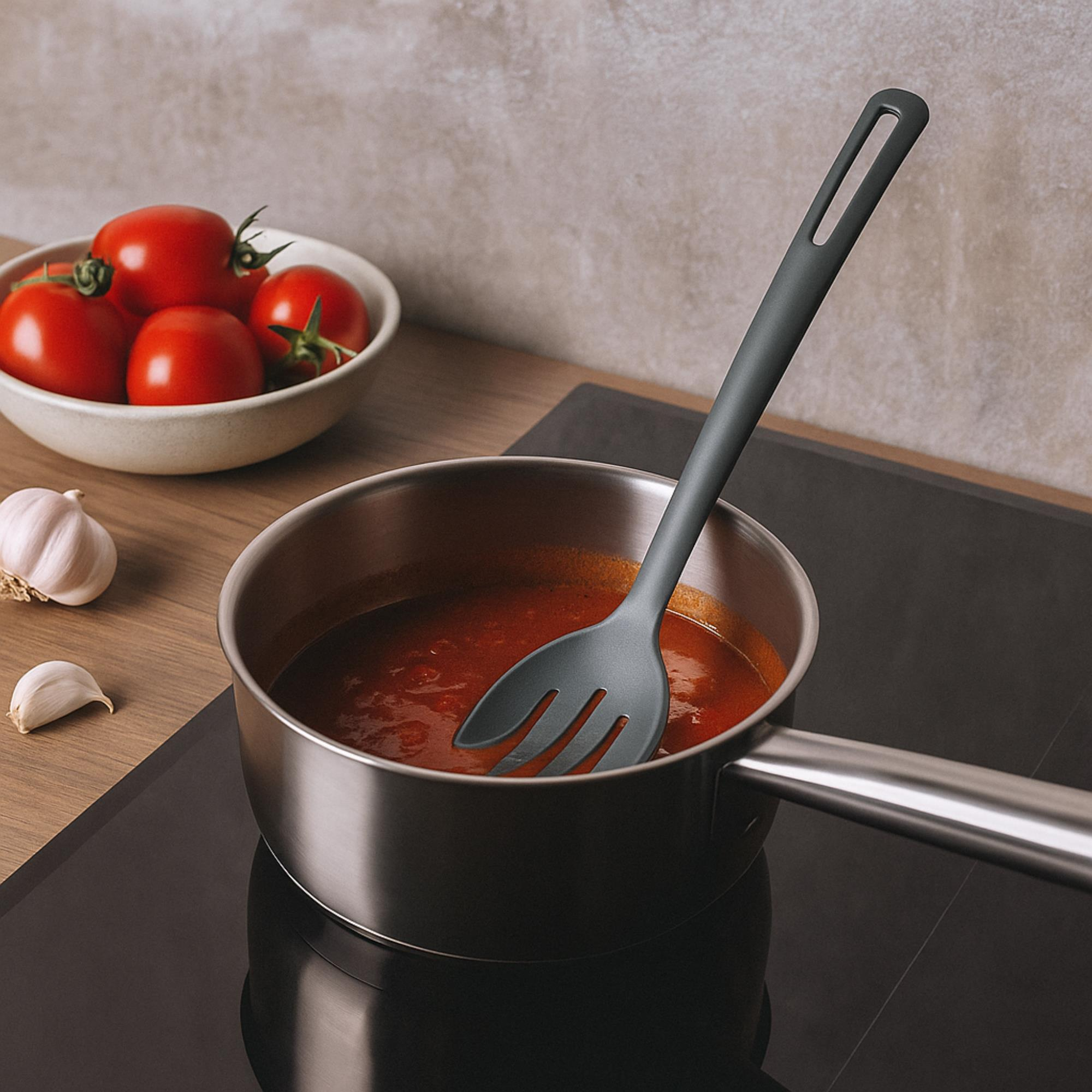 Una olla de salsa de tomate en una estufa, tomates y ajo en la mesa, una cuchara en la olla.