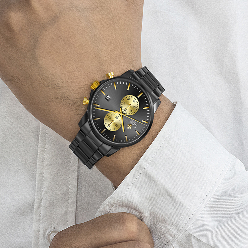 Eine schwarze Armbanduhr mit goldenen Akzenten befindet sich am Handgelenk einer Person, die ein weißes Hemd trägt.