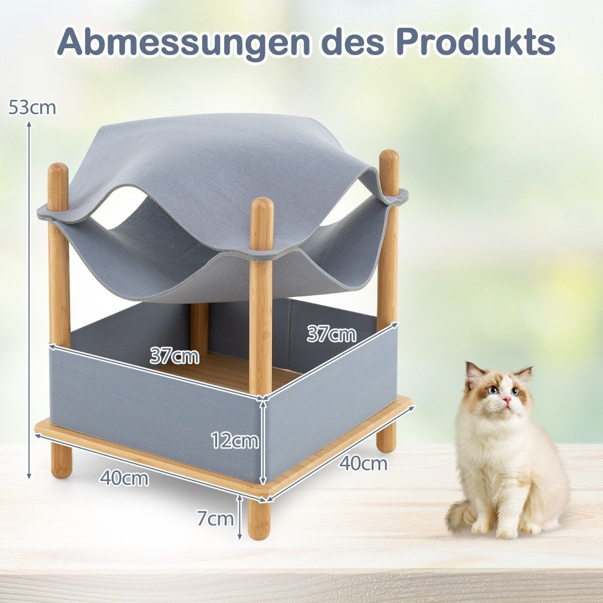 Una cama para gatos con dimensiones, gato sentado al lado. La cama es gris y de madera. Gato blanco con ojos azules.