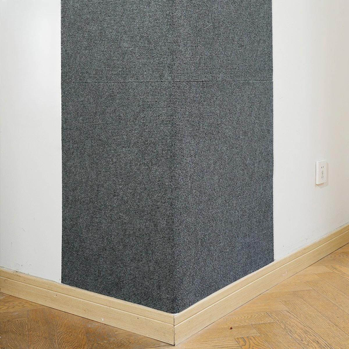 Zimmerecke mit grau strukturierter Wand, weißen Wänden, Holzsockelleisten und Parkettboden.