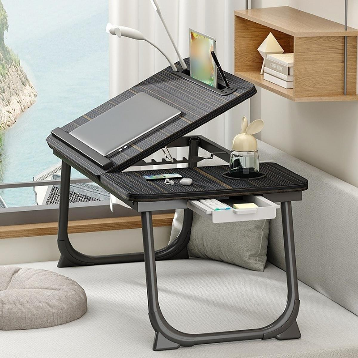 Ein schwarzer Laptop-Tisch mit Laptop, Tablet und Zubehör. Im Hintergrund ein Fenster und ein Regal. Der Tisch steht auf einem Sofa.