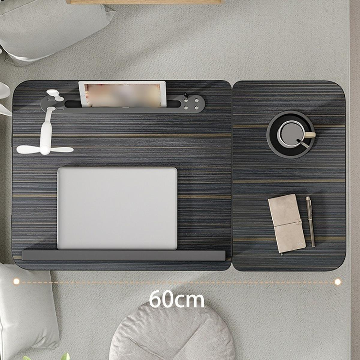 Draufsicht auf einen Laptop-Schreibtisch. Er hat einen Laptop, einen Ventilator, Kaffee, ein Notizbuch und ein Tablet. Der Schreibtisch steht auf einem Bett.